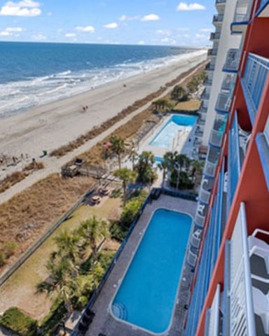 Beachfront condo building with pool overlooking sandy beach and ocean