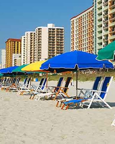 Beach with colorful umbrellas and lounge chairs, high-rise hotels in background