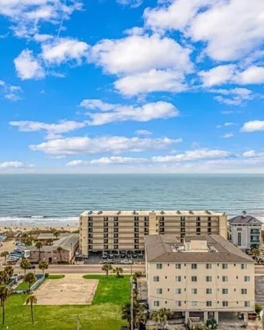 Elevated view of beachfront resort buildings with ocean, sandy beach, and blue sky with white clouds