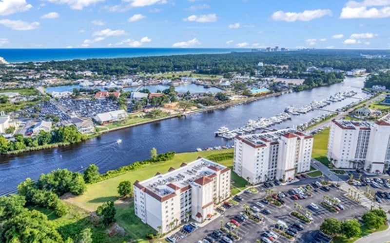 Aerial view of riverside town with apartment buildings, parking lot, and green spaces along winding river