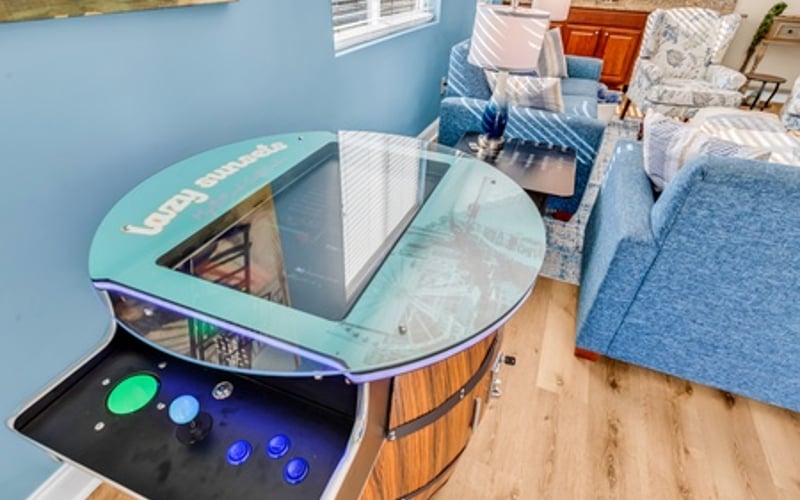 Bedroom with blue walls, glass-top desk with arcade game controls, and blue upholstered bed
