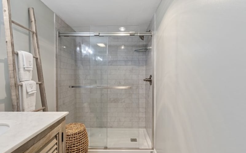 Modern bathroom with walk-in shower, glass enclosure, white subway tile, and wooden vanity with sink