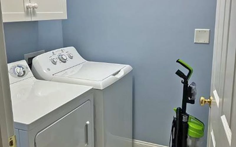 Laundry room with white washer and dryer, blue walls, and cleaning supplies in corner