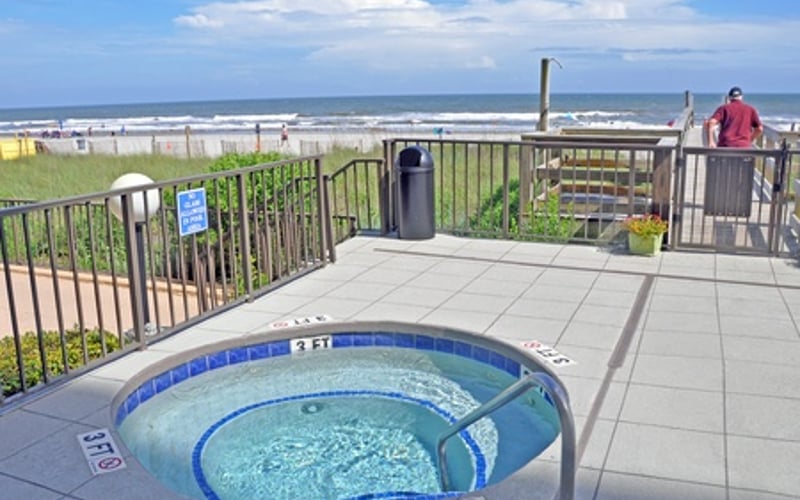 Hot tub on rooftop deck with ocean and beach view in background