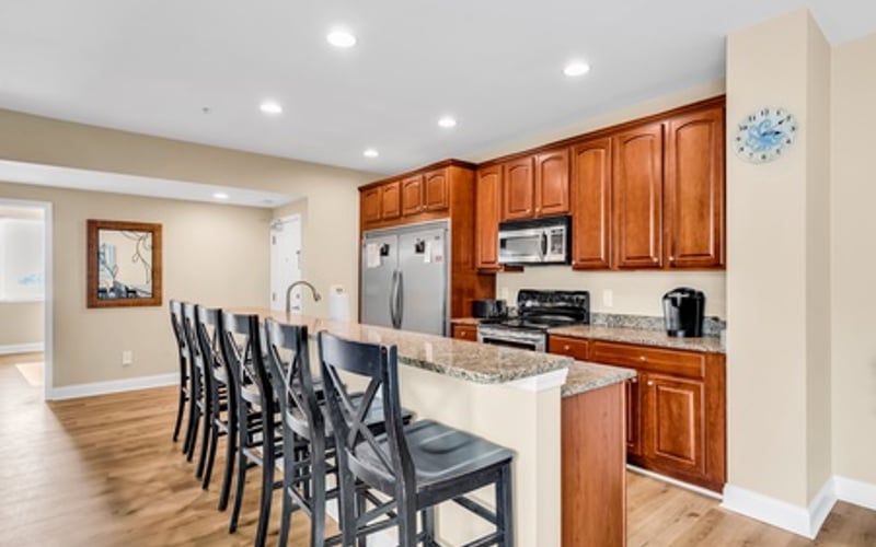 Modern kitchen with wood cabinets, stainless steel appliances, and island with black bar seating