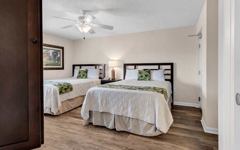 Bedroom with two twin beds, wooden flooring, ceiling fan, and white walls