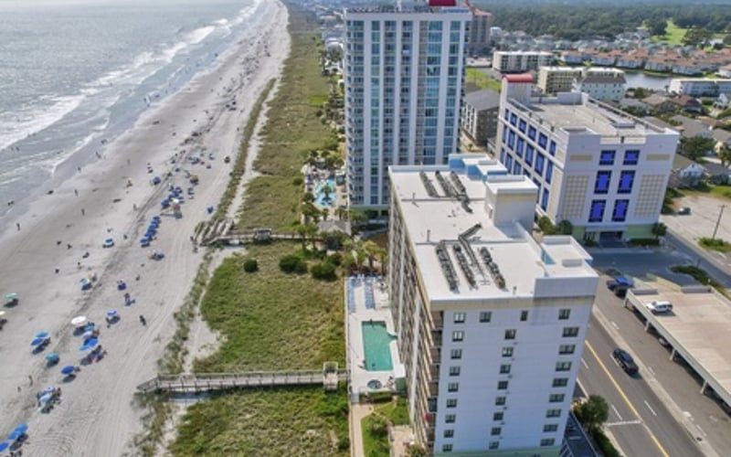 Aerial view of beachfront high-rise buildings with sandy beach and ocean waves