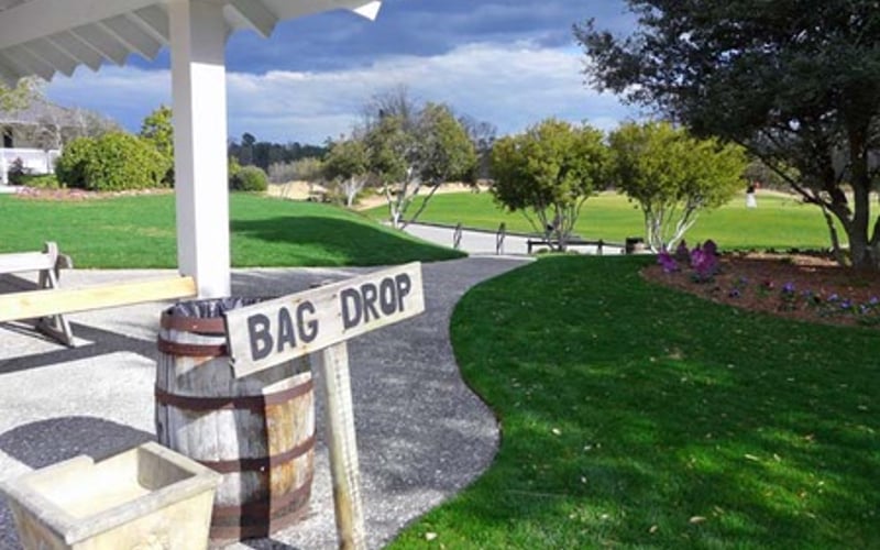 Bag drop station near covered patio with expansive green lawn and trees beyond