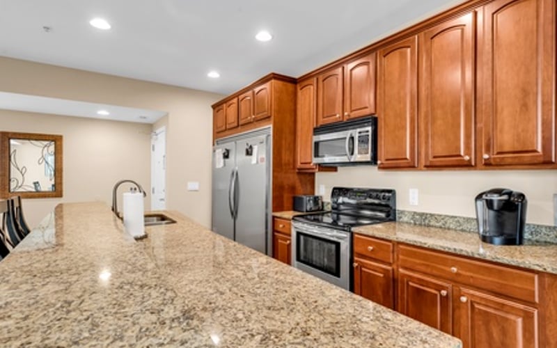 Modern kitchen with wood cabinets, granite countertop, stainless steel appliances, and island seating