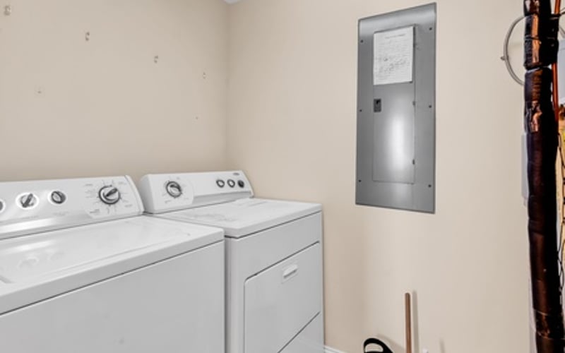 Laundry room with white washer and dryer, utility door, and beige walls