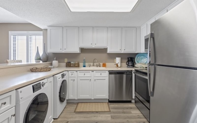 Modern kitchen with white cabinetry, stainless steel appliances, and wood-look flooring