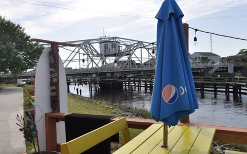 Waterfront deck with blue umbrella overlooking drawbridge and wooden docks