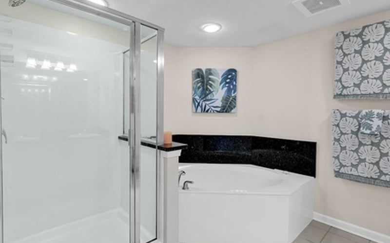 Modern bathroom with glass shower enclosure, white soaking tub, and decorative wall art