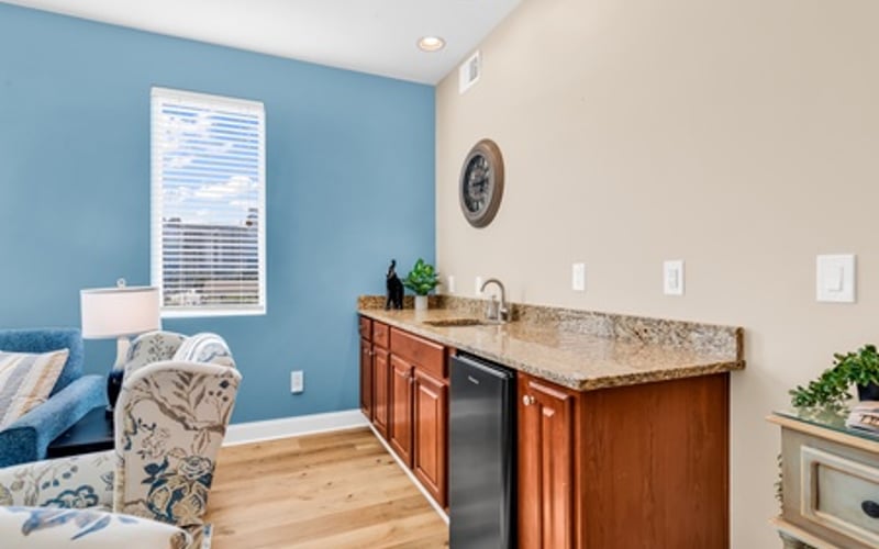 Kitchen with wood cabinets and granite countertop, blue accent wall, and adjacent seating area with window