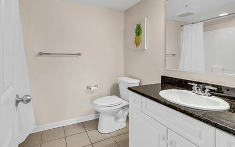 Bathroom with white vanity, black granite countertop, white toilet, and tile flooring