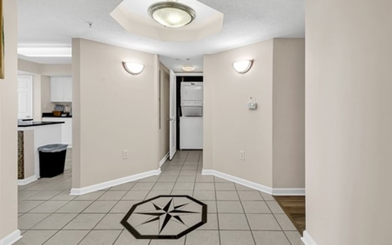 Hallway with geometric tile floor pattern, recessed lighting, and kitchen visible on left
