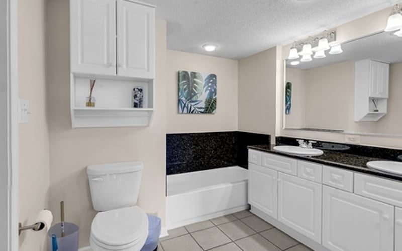 Bathroom with white cabinetry, double vanity, soaking tub, and tile flooring